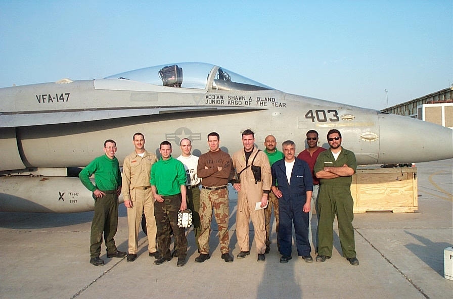 A grateful pilot and a maintenace team infront of a damaged F/A-18
