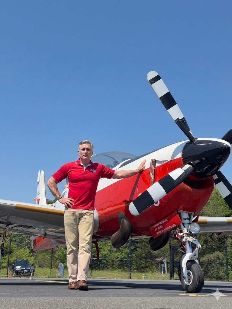 Tony Wright in a red Aviation Adventures polo standing next to the Shorts S312 Tucano T Mk 1 on the ramp.