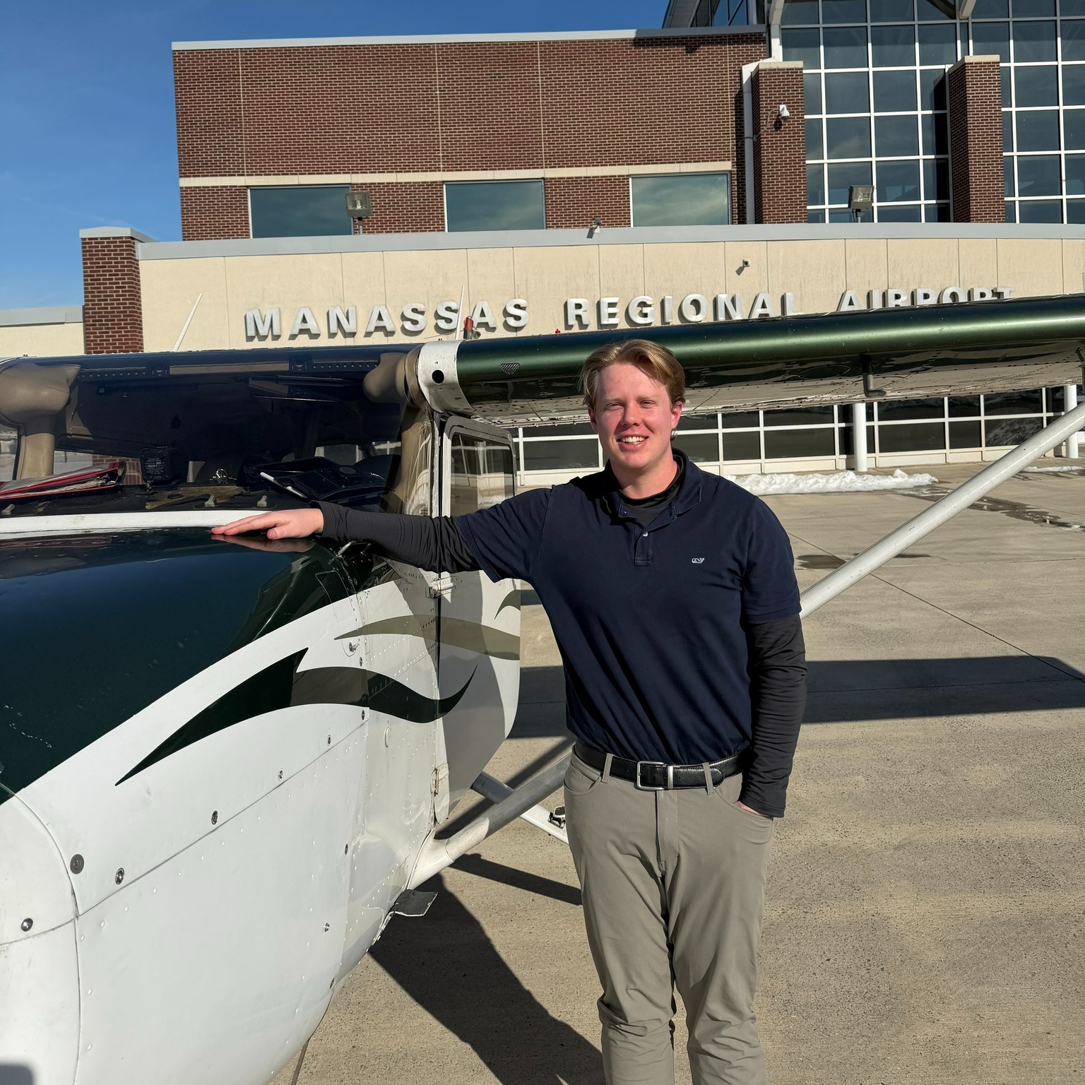 Student standing next to his Cessna, smiling.