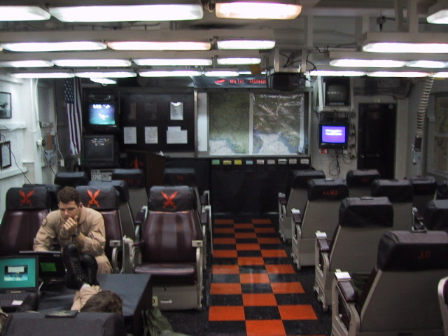 The squadron ready room: rows of high-back chairs with crossed-cutlass seat covers, chart boards and the duty desk.